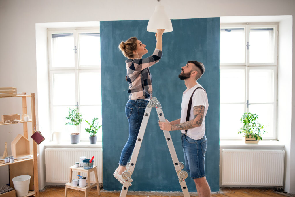 mid adults couple changing light bulb indoors at home, relocation and diy concept.